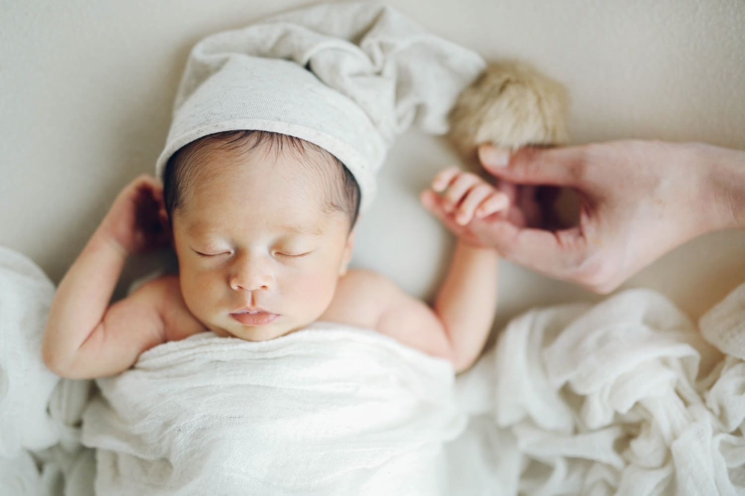 白いベッドの上で眠る新生児のニューボーンフォト